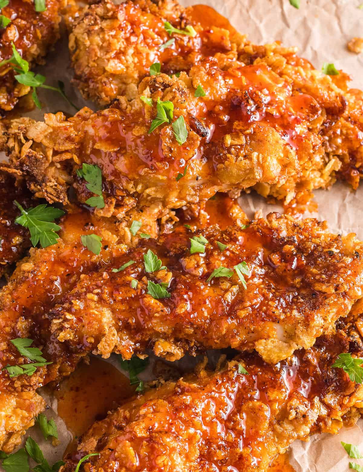 Juicy chicken tenders are coated with a crunchy cornflake breading, air fried until perfectly golden, then liberally drizzled with a sweet and spicy homemade hot honey sauce!