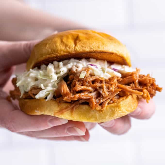 holding a pulled pork sandwich with coleslaw