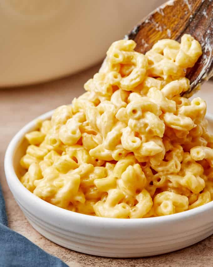 spooning mac and cheese into a small white bowl