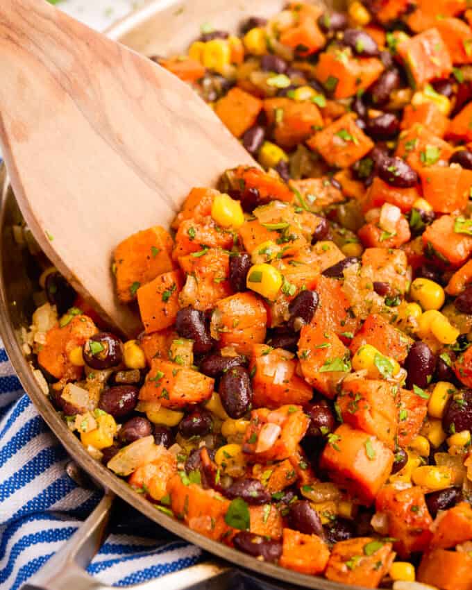 wooden serving spoon scooping some black bean taco filling with sweet potatoes