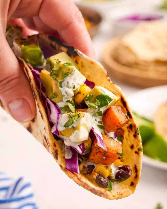 holding a black bean taco in a charred flour tortilla