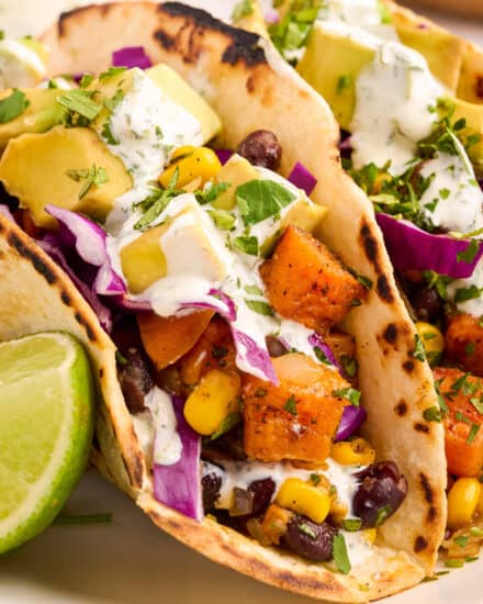 These spiced sweet potato and black bean tacos are topped with an incredible honey lime crema, and are sure to make even non-vegetarians fall in love with meatless meals! #meatlessmonday