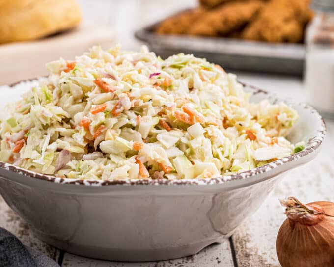 serving bowl of coleslaw on a white table.