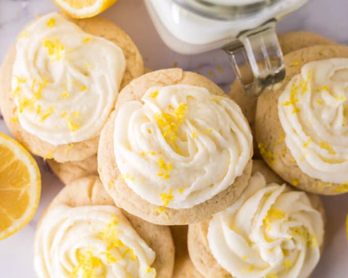 pile of lemon frosted sugar cookies with a glass of milk
