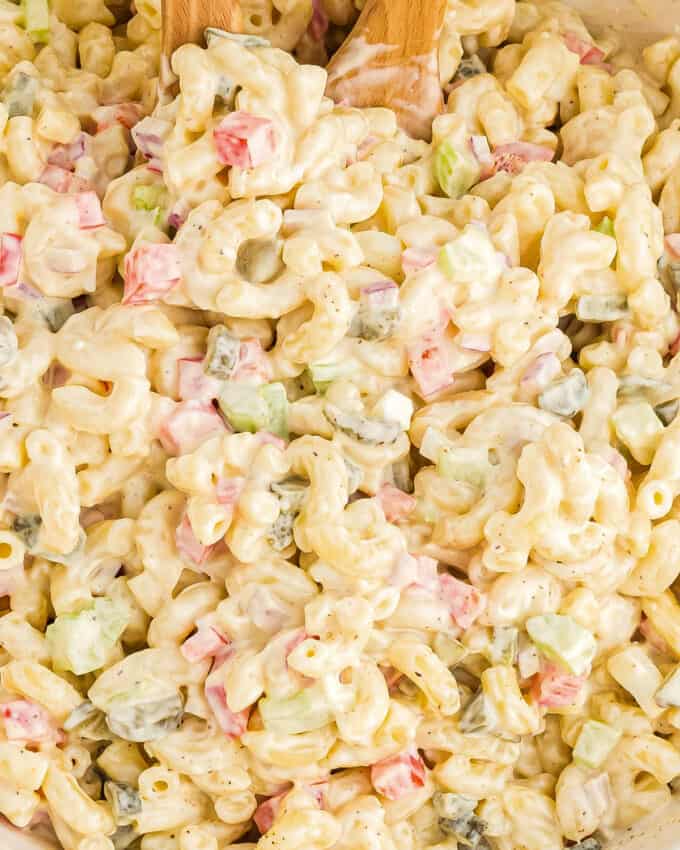 close up view of a serving spoon scooping macaroni salad