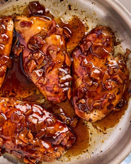 overhead view of a skillet with chicken breasts topped with a bacon glaze.