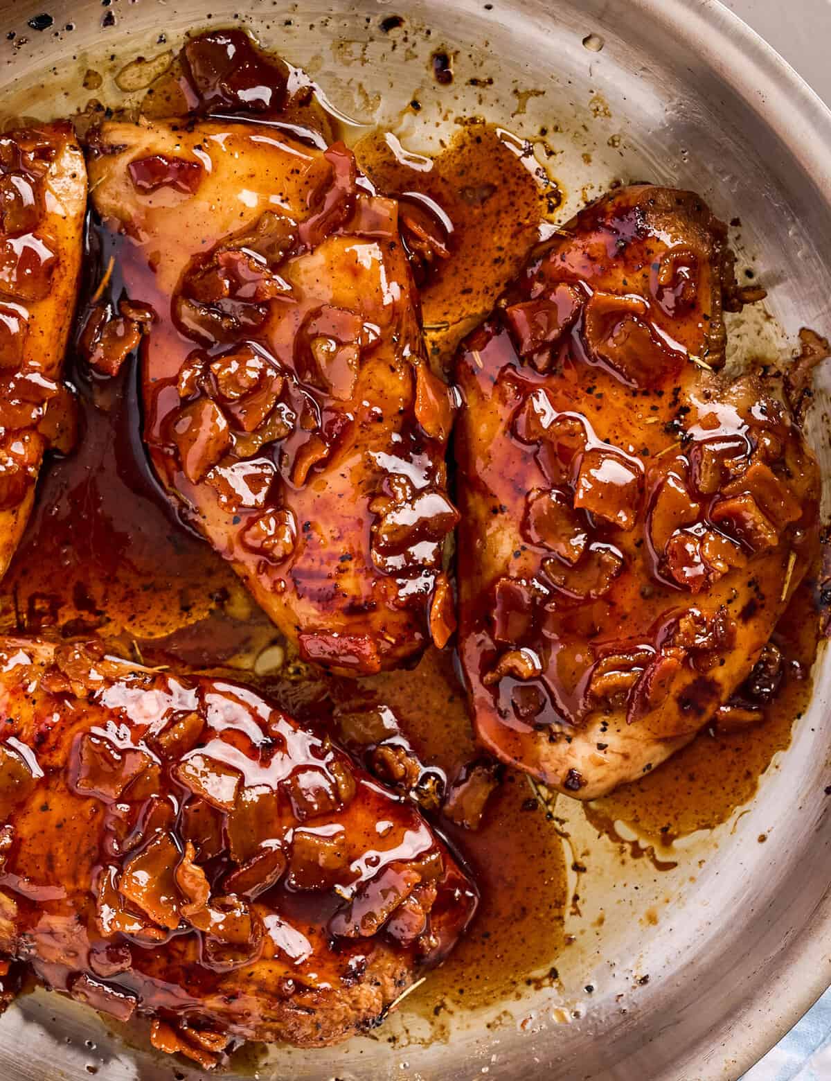 overhead view of a skillet with chicken breasts topped with a bacon glaze.