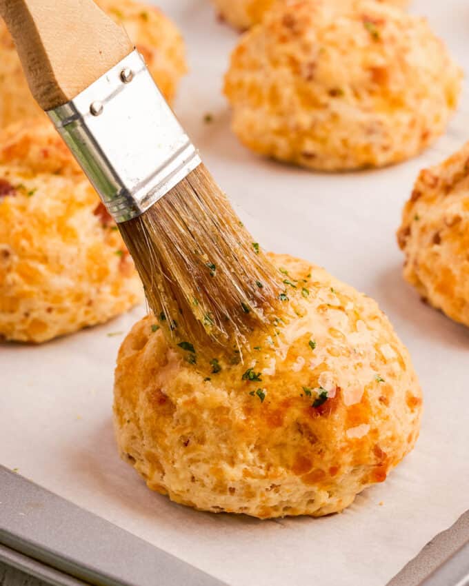 brushing a buttermilk biscuit with garlic herb butter.