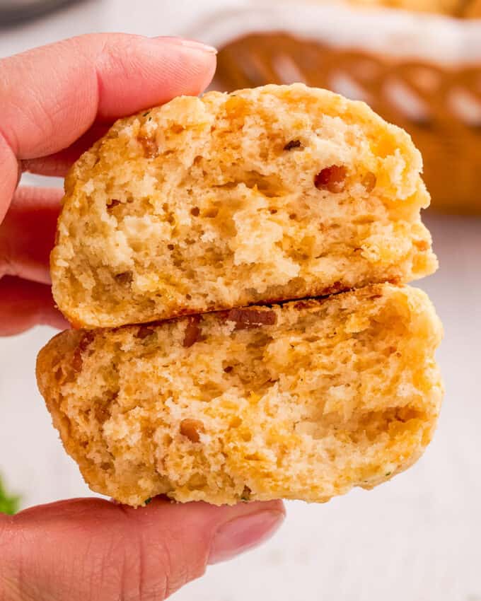 hand holding a bacon buttermilk biscuit cut in half to show the inside.