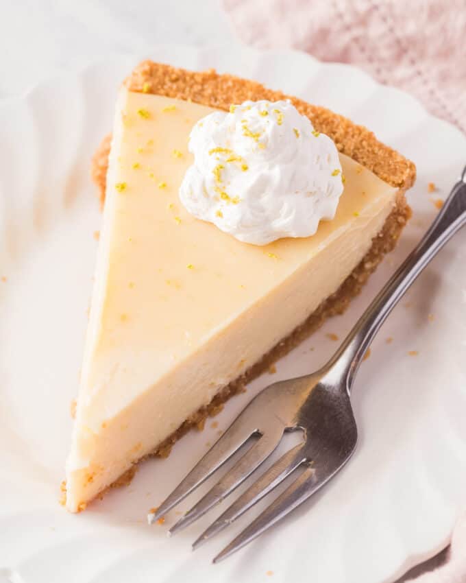 slice of key lime pie garnished with a dollop of whipped cream on a white plate with a fork.