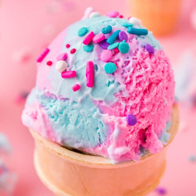 cotton candy ice cream cone with sprinkles on top.