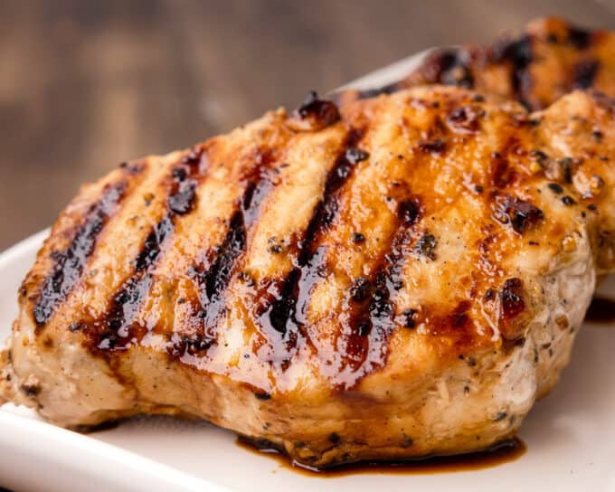 close view of grilled pork chops on a white platter.