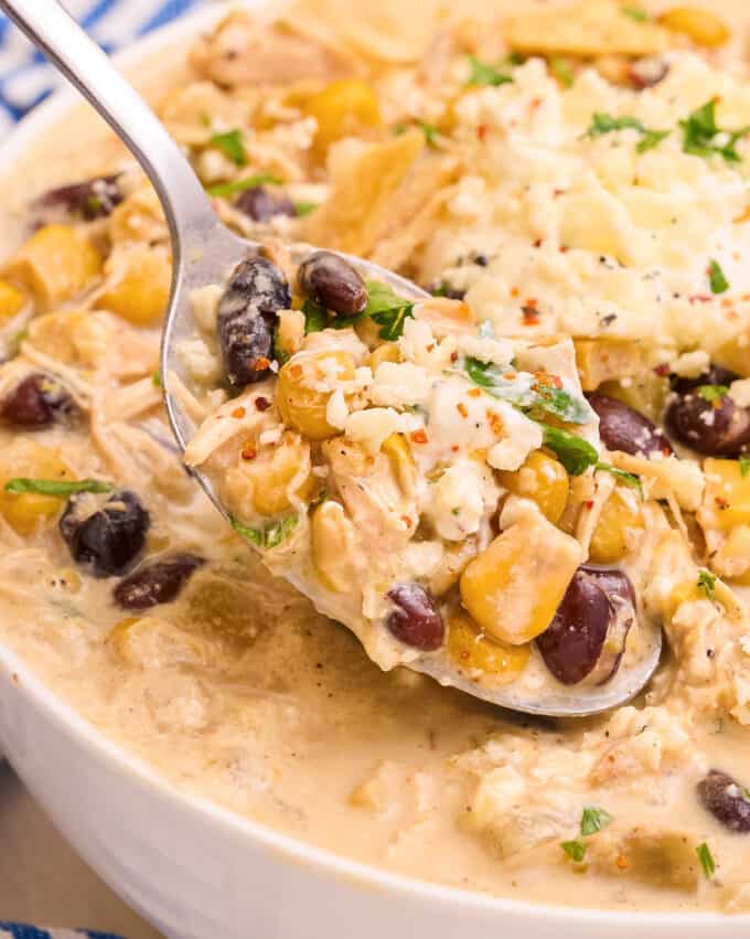 spoonful of street corn chicken chili resting on top of a bowl of chili.