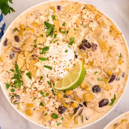 overhead photo of a white bowl of chicken street corn chowder with a lime wedge.