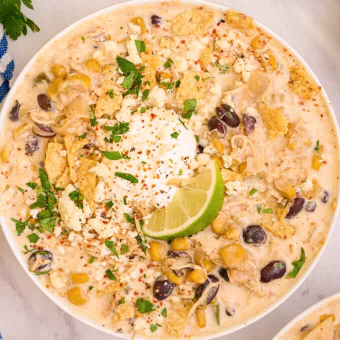 overhead photo of a white bowl of chicken street corn chowder with a lime wedge.