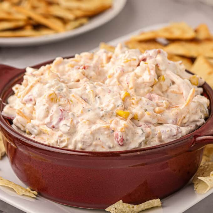 brown serving bowl of creamy rotel ranch dip with chips for dipping.