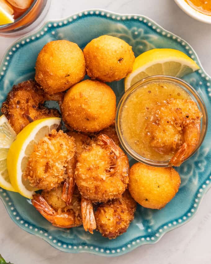 blue plate filled with coconut shrimp and jalapeno hush puppies.
