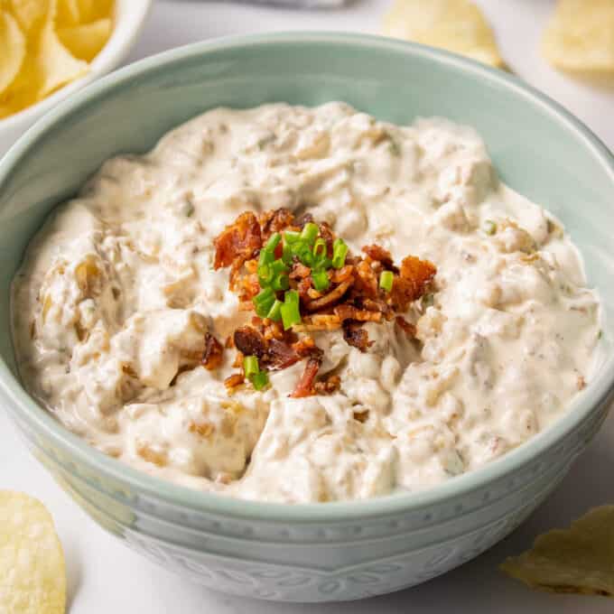 blue bowl of onion dip with bacon on top.