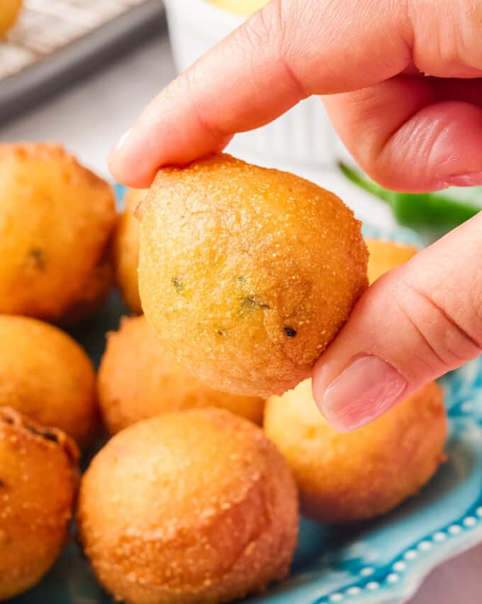 holding a hush puppy between two fingers.