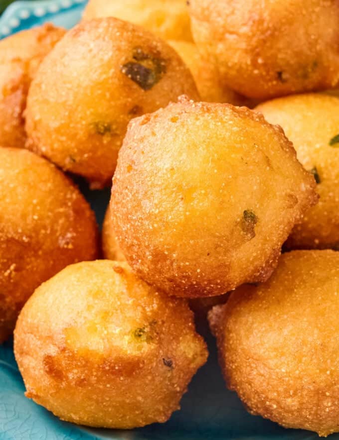 Tender balls of slightly sweetened cornmeal batter studded with fresh jalapeño peppers are fried until perfectly golden brown and tender! Homemade hush puppies are amazing as a side dish alongside so many meals, but especially seafood (fried seafood in particular).