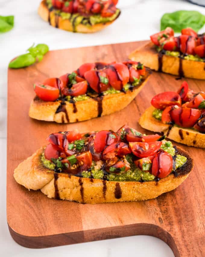 wooden board topped with pesto and tomato bruschetta.