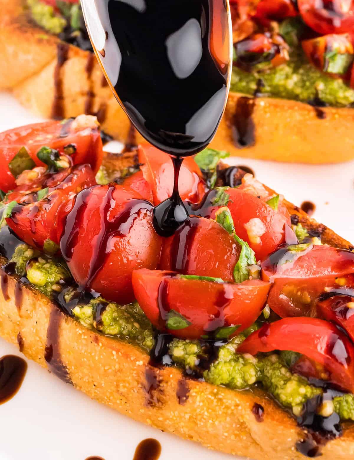 Crisp golden brown baguette slices are topped with a flavorful basil pesto, then a simple tomato bruschetta topping and drizzled with a sweet and tangy balsamic glaze. This is the ultimate summer appetizer, and sure to be a true crowd-pleaser!