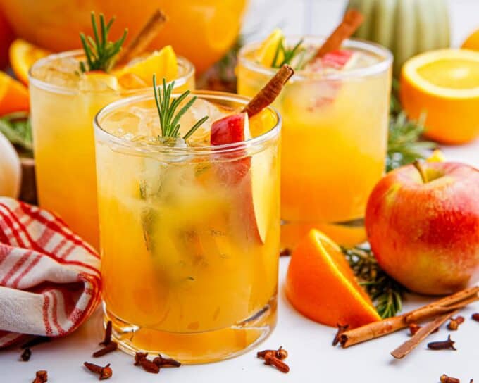 multiple glasses of apple cider punch on a white table.