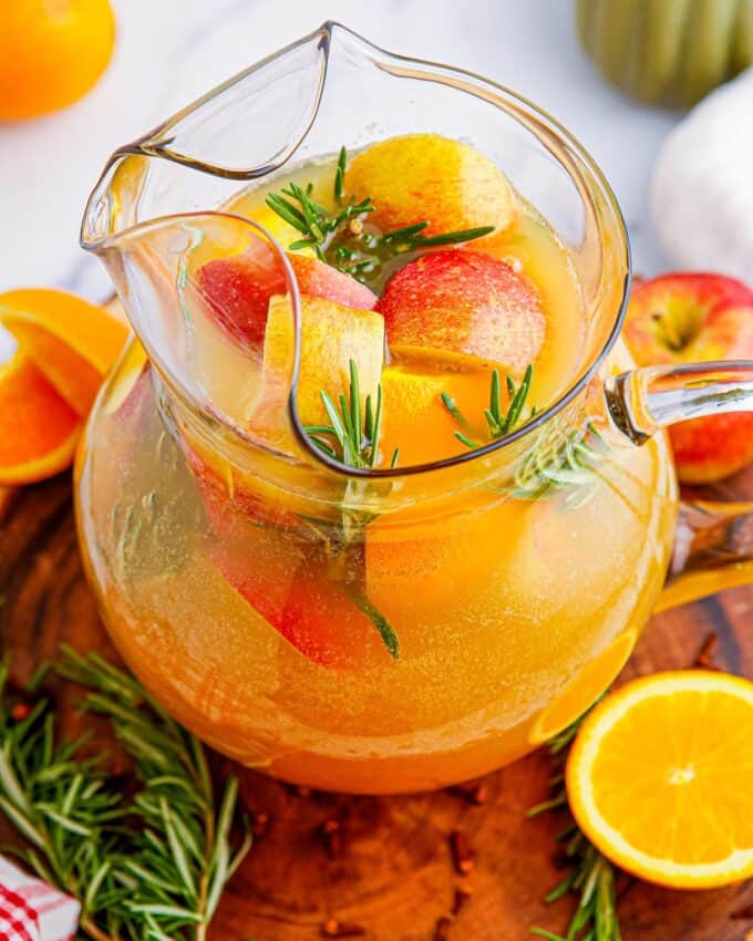 glass pitcher of cider punch on wooden serving board.