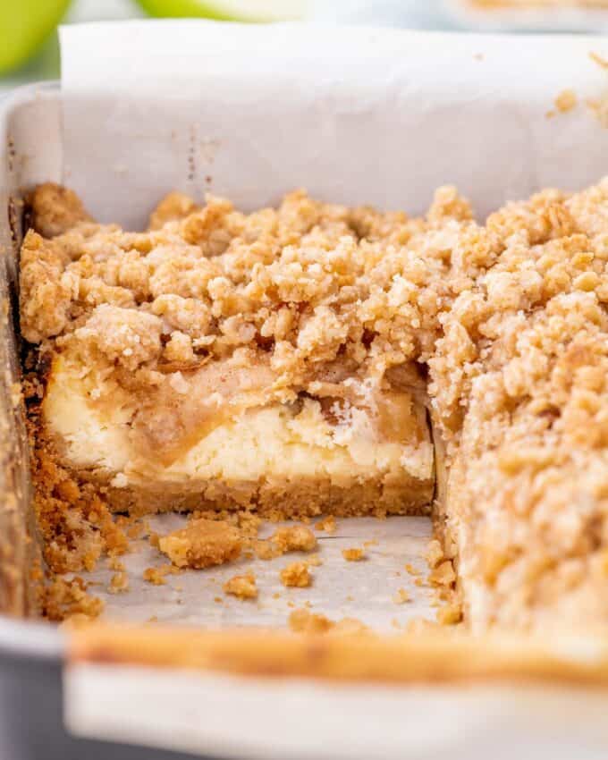 baking pan of cheesecake bars with a bar taken out so you can see the side-view of a bar in the pan.