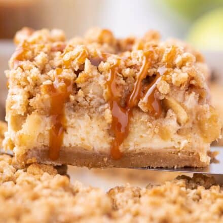 Serving a caramel apple cheesecake bar drizzled with caramel sauce.