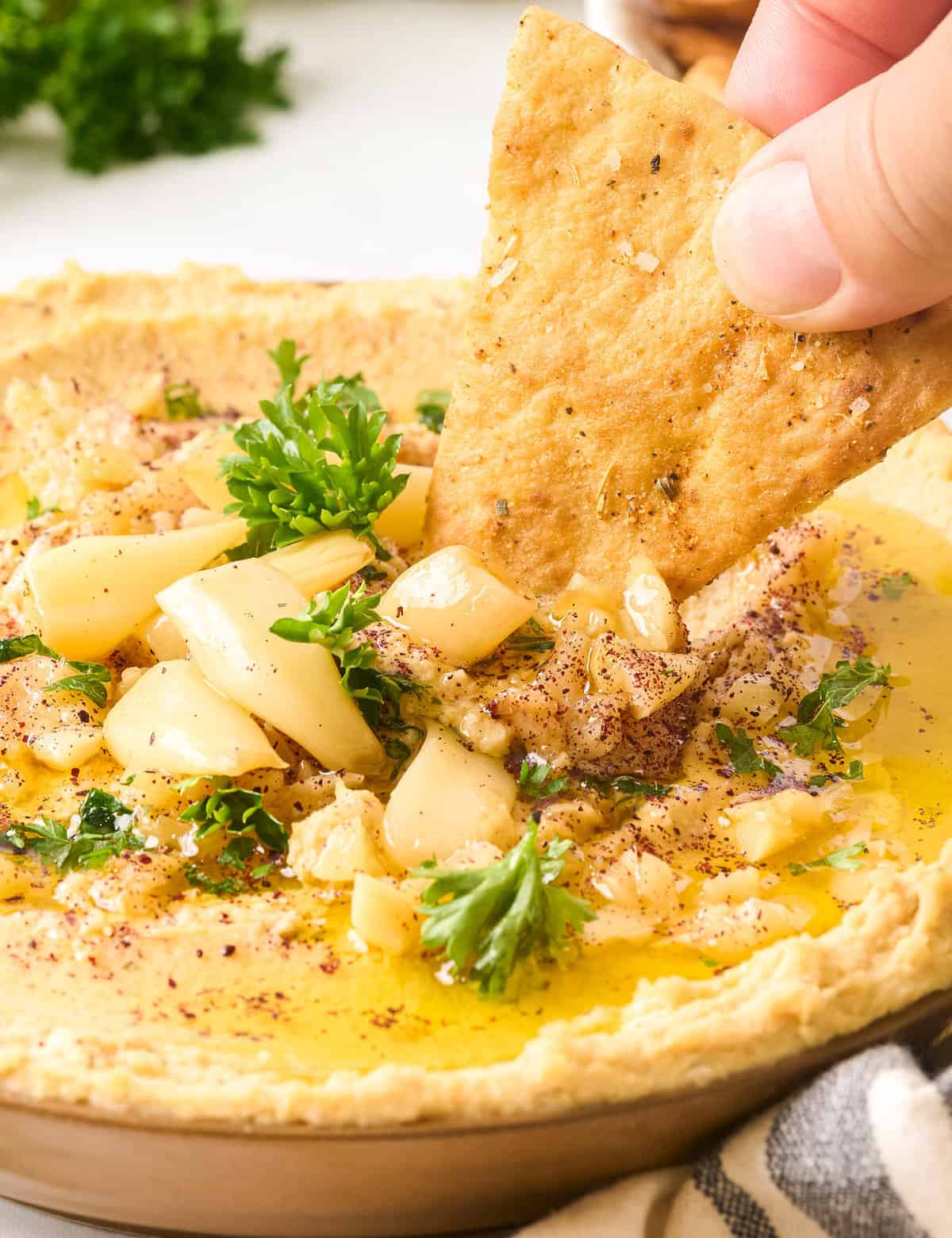 This homemade roasted garlic hummus recipe is creamy, light, and SO much better than store-bought. The sweet roasted garlic brings a bold burst of flavor, and using canned chickpeas eliminates the need for any soaking or peeling, so you can dip your pita chips or vegetables in this delicious dip in no time!