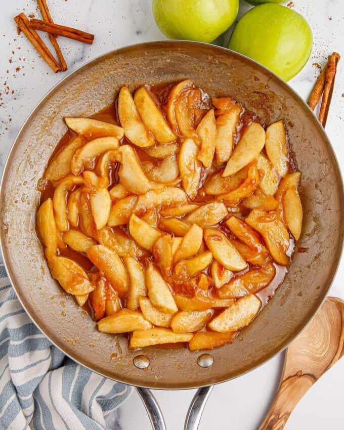 fried apples in stainless steel skillet on white table.
