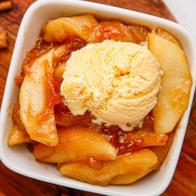 overhead photo of a square bowl filled with fried apples and a scoop of vanilla ice cream.