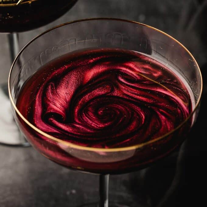 black vodka martini with red luster dust swirled into it.