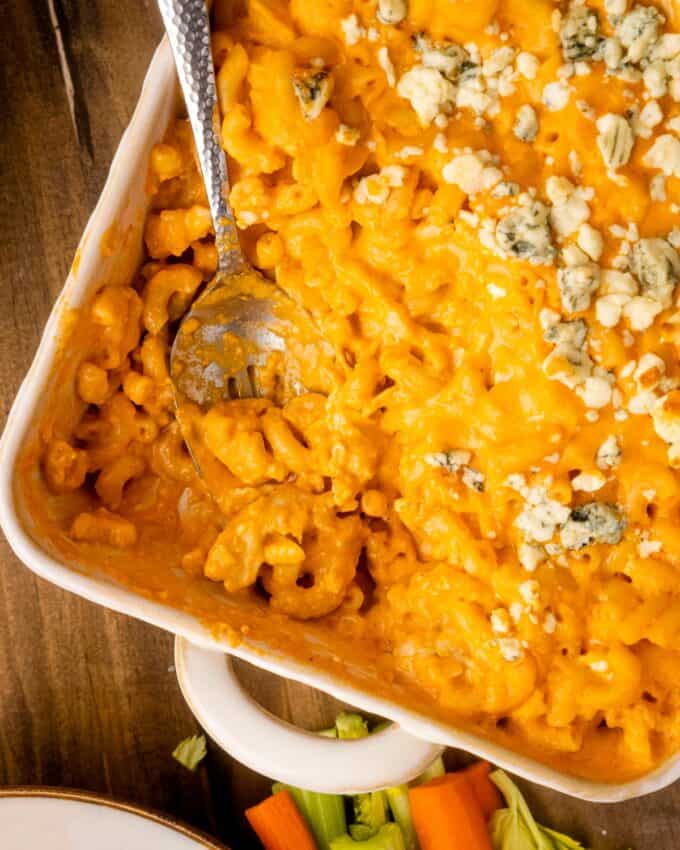 baking dish full of buffalo mac and cheese with several scoops taken out.