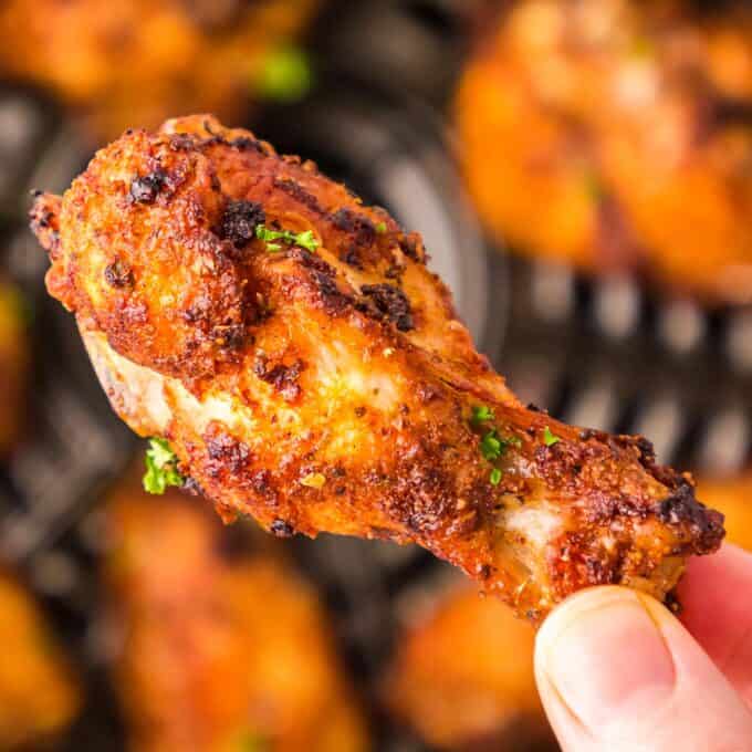 holding a crispy chicken wing that was cooked in an air fryer.