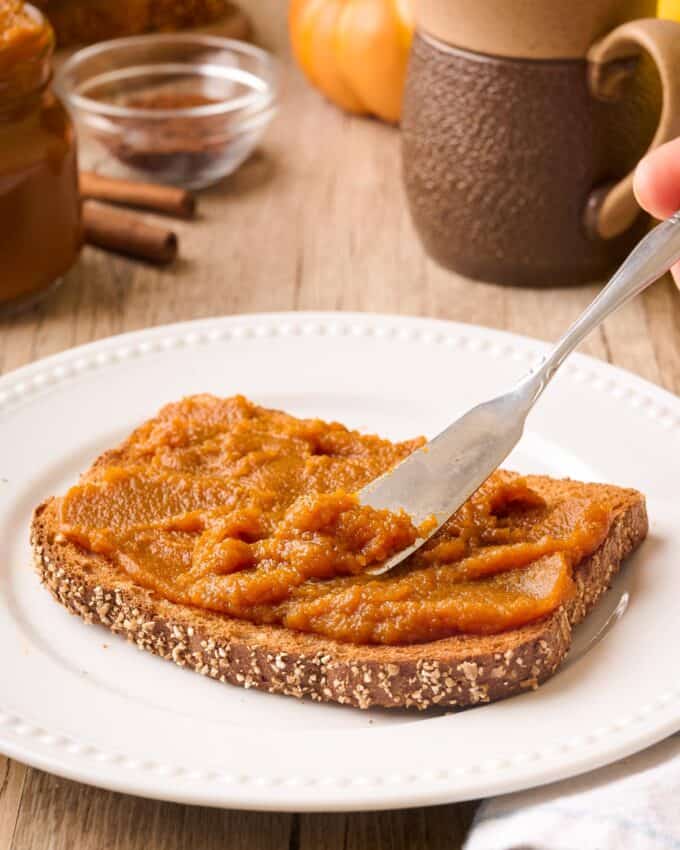 spreading pumpkin butter on a piece of toast.