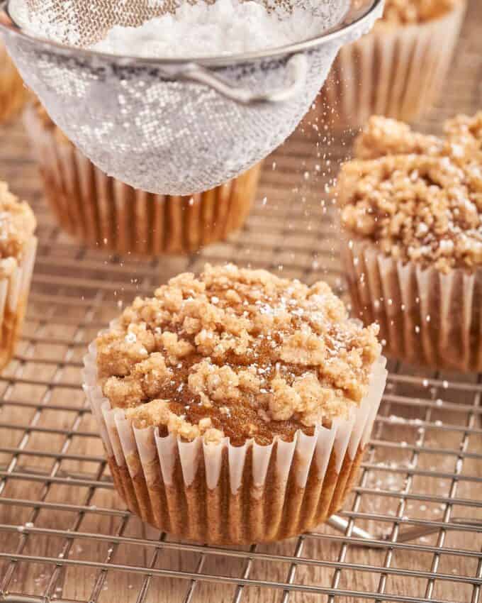 dusting a pumpkin muffin with powdered sugar.