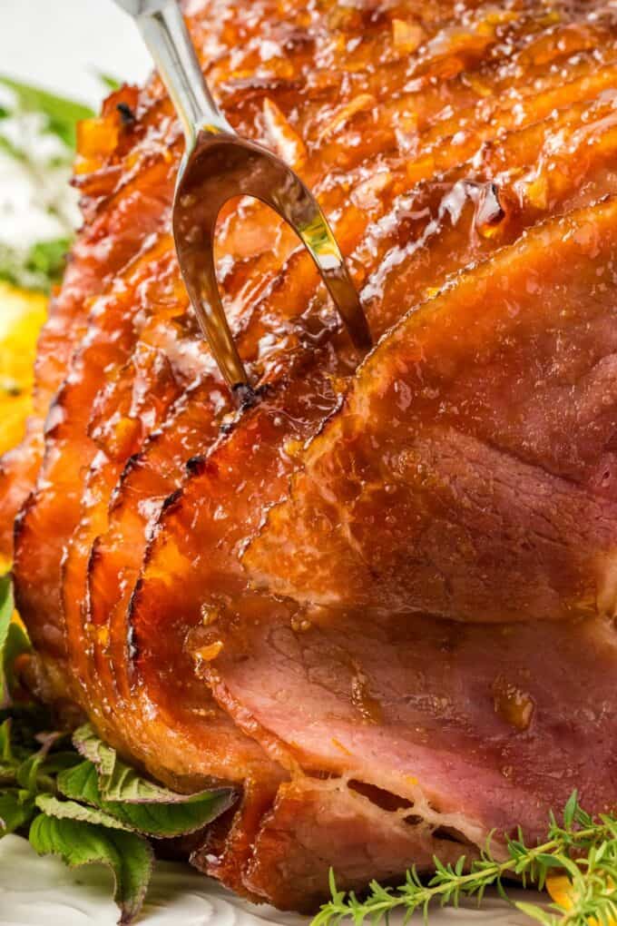 carving fork piercing a spiral sliced glazed ham.