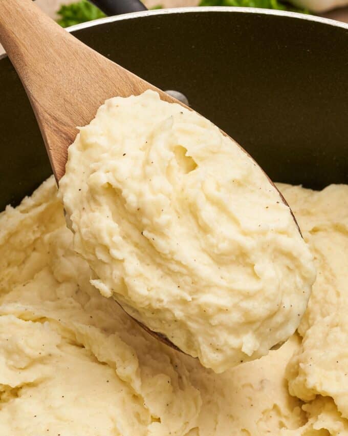wooden spoon scooping mashed potatoes out of a pot.