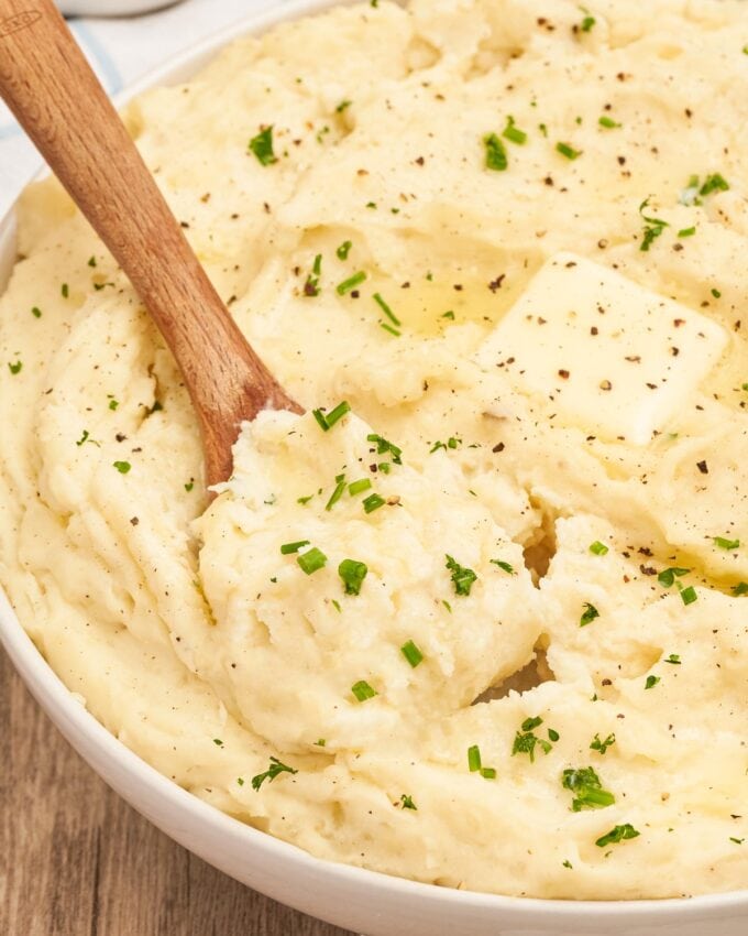 serving a scoop of mashed potatoes out of a white bowl.