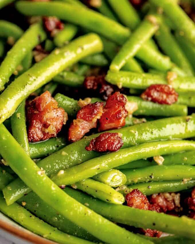 close up of green beans in a bowl with cooked bacon.