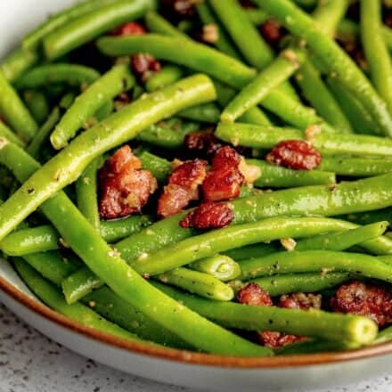 grey bowl of cooked green beans with bacon and garlic.