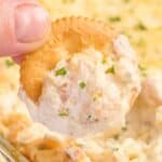 close up photo of a ritz cracker that's been dipped in cheesy shrimp dip.