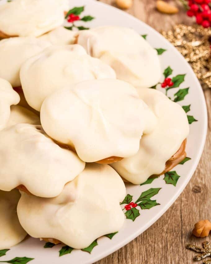 stack of white chocolate covered caramel nut cluster candies on a holiday plate.