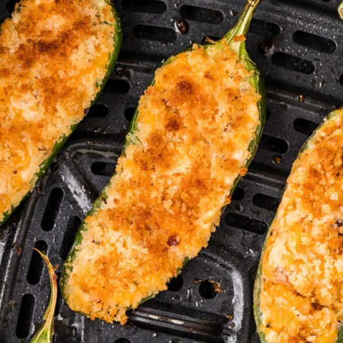 "baked" jalapeño poppers in a black air fryer basket.