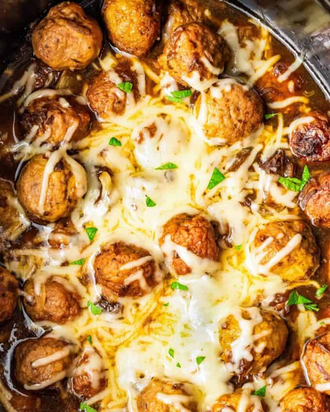 slow cooker full of french onion meatballs covered in melted cheese.