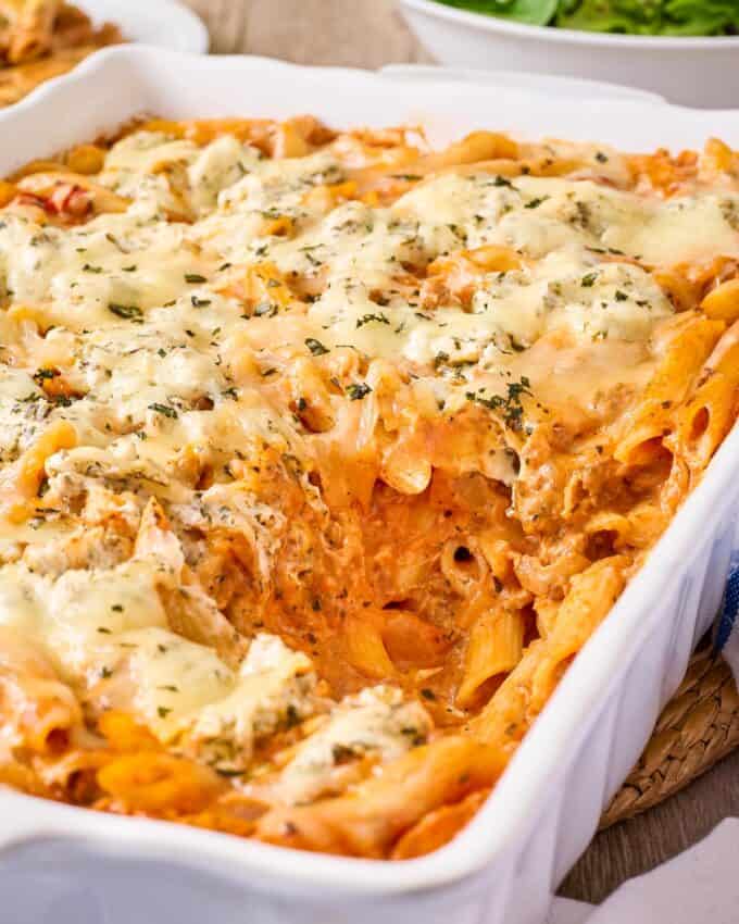 baking dish of baked penne with a scoop taken out.