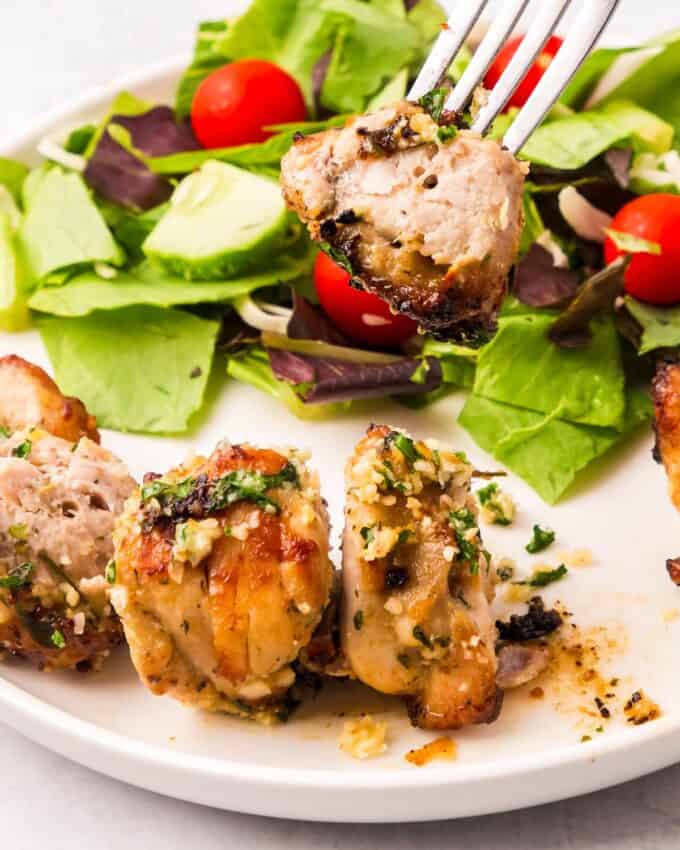 fork holding a piece of garlic parmesan chicken.