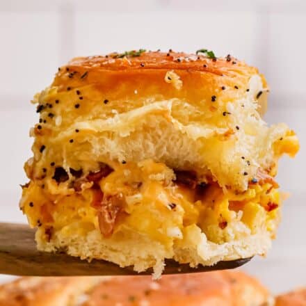 close photo of a bacon egg and cheese slider on a wooden serving spatula.